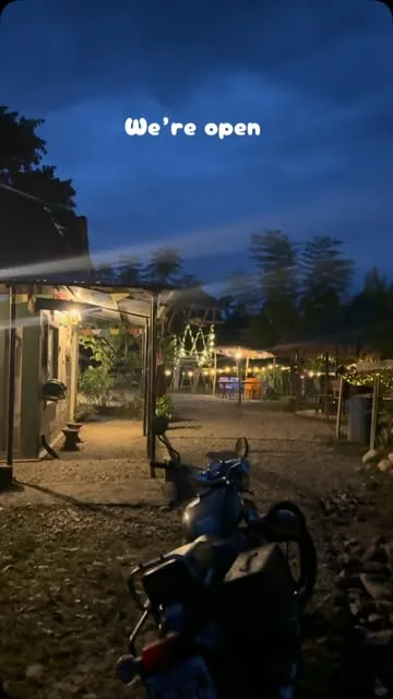 The lane between the huts lit by string lights at blue hour.